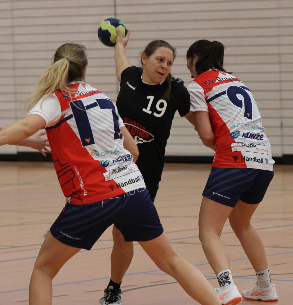 Foto zeigt eine Peißenberger Spielerin beim Abwurf zwischen zwei Abwehrspielerinnen vom SV Bruckmühl.