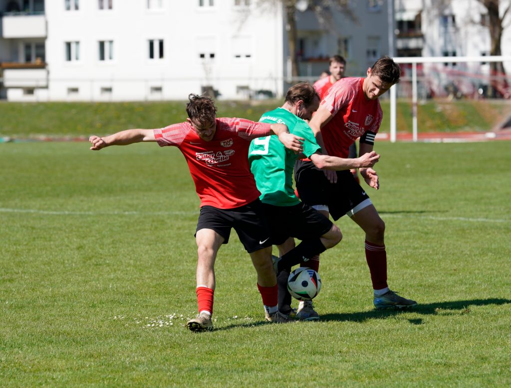 Foto zeigt zwei Peißenberger Spieler und in der Mitte einen Gegner mit dem Ball am rechten Fuß. 