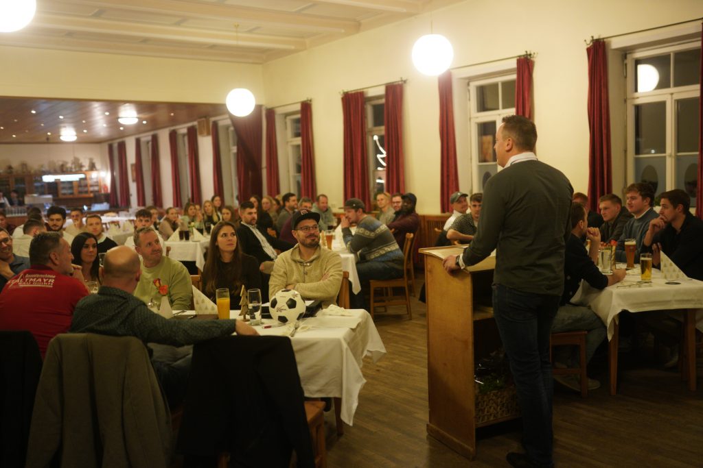 Bild zeigt von hinten in Richtung Saal mit den Mitgliedern Abteilungsleiter Johann Schwaller stehen am Rednerpult.