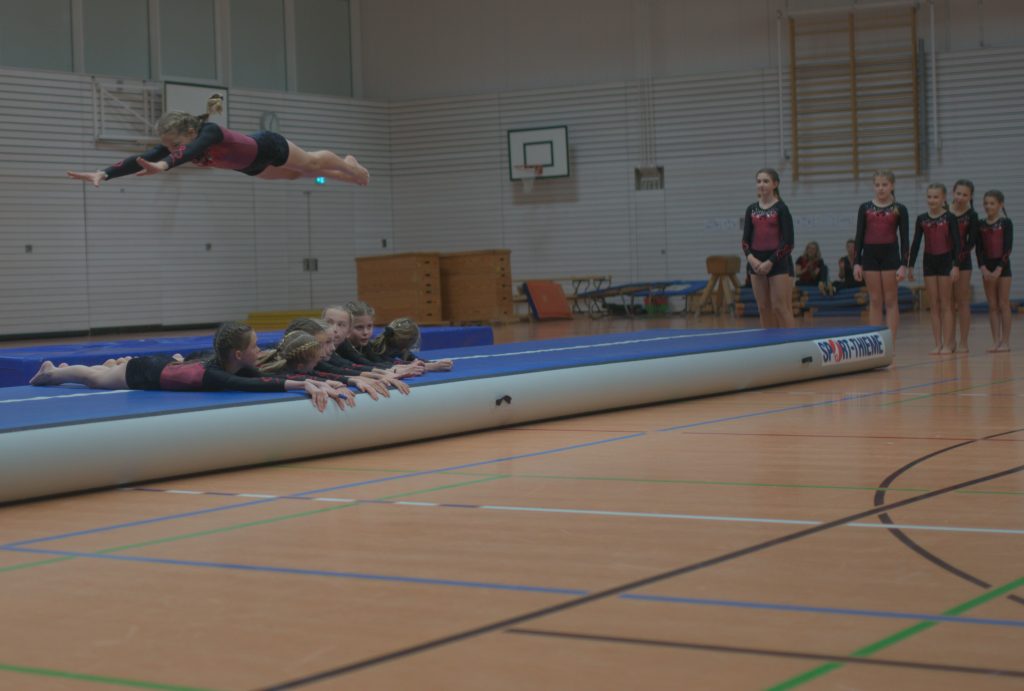 1 Foto vom Weihnachtsturnen in der Glückauf Turnhalle. Bild zeigt Akrobatik Flug über 6 liegende.