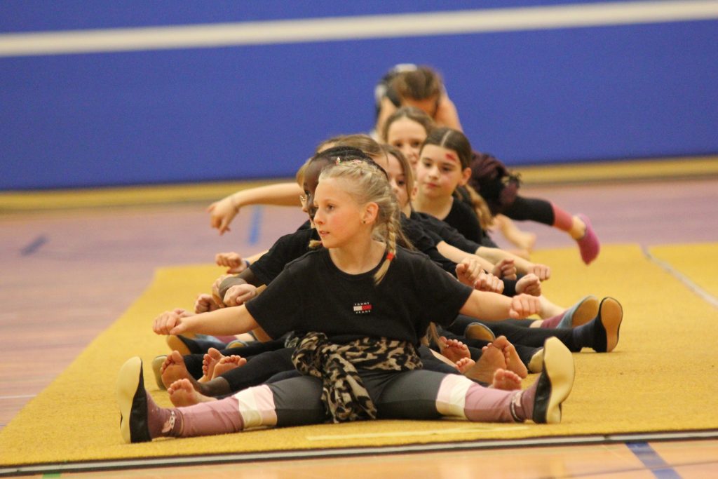 8 Foto vom Weihnachtsturnen in der Glückauf Turnhalle zeigt ein sitzendes Gruppenbild von Teilnehmerinnen.