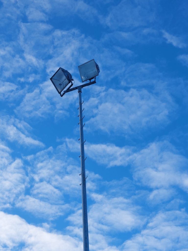 Foto zeigt zwei Halogen-Metalldampflampen und den oberen Teil des Mastens auf dem Trainingsplatz.